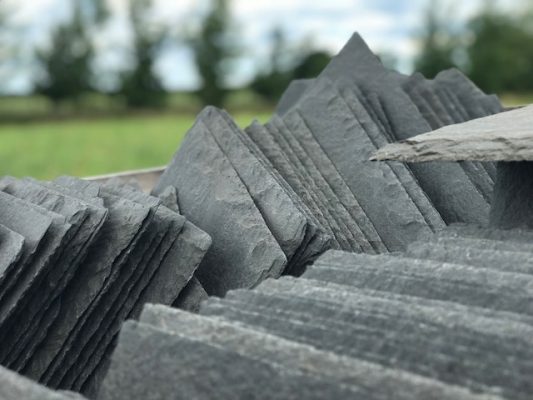 image showing reclaimed slates in a pallet with blurred countryside background, The Reclaimed Company